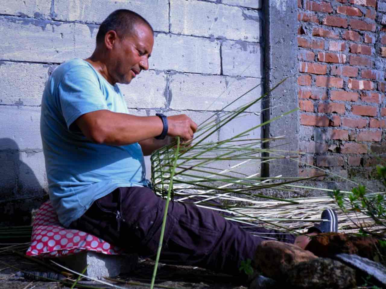 Badal Chettri weaves a bamboo basket outside his house in Naya Basti.