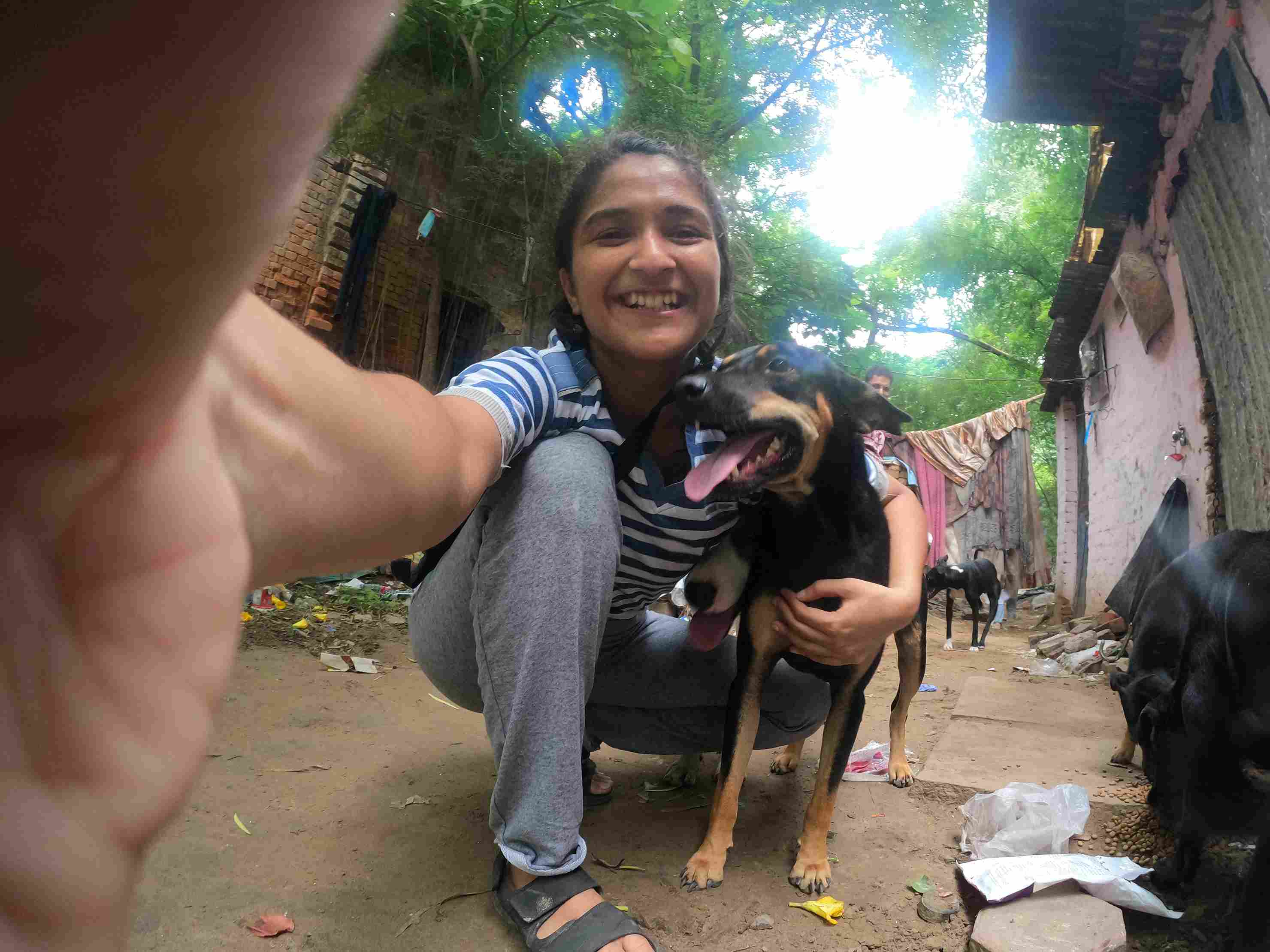 Mouli Mehrotra taking a fun selfie with the street dogs she cares for, surrounded by happy, well-fed animals.