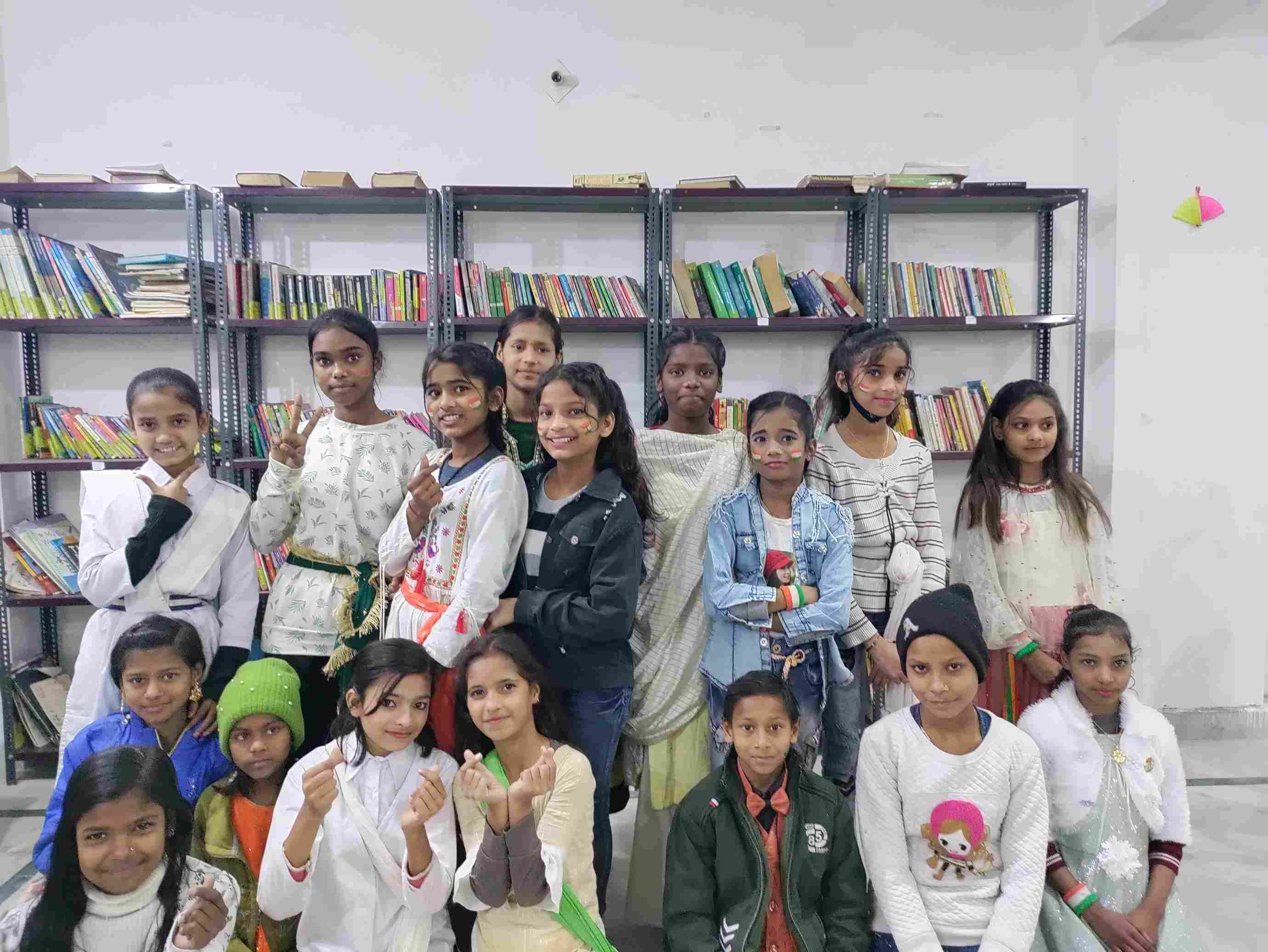 A group of girls standing in front of newly set up bookshelves in their school.