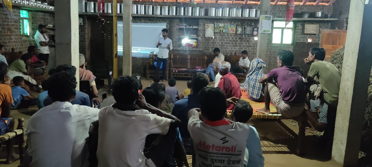 Community members and volunteers conducting a screening and meeting to discuss local issues in the village.