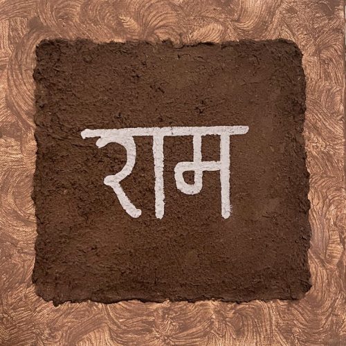 'Ram' written and displayed on a brown background made from natural materials: cow dung, white charcoal, and sand.