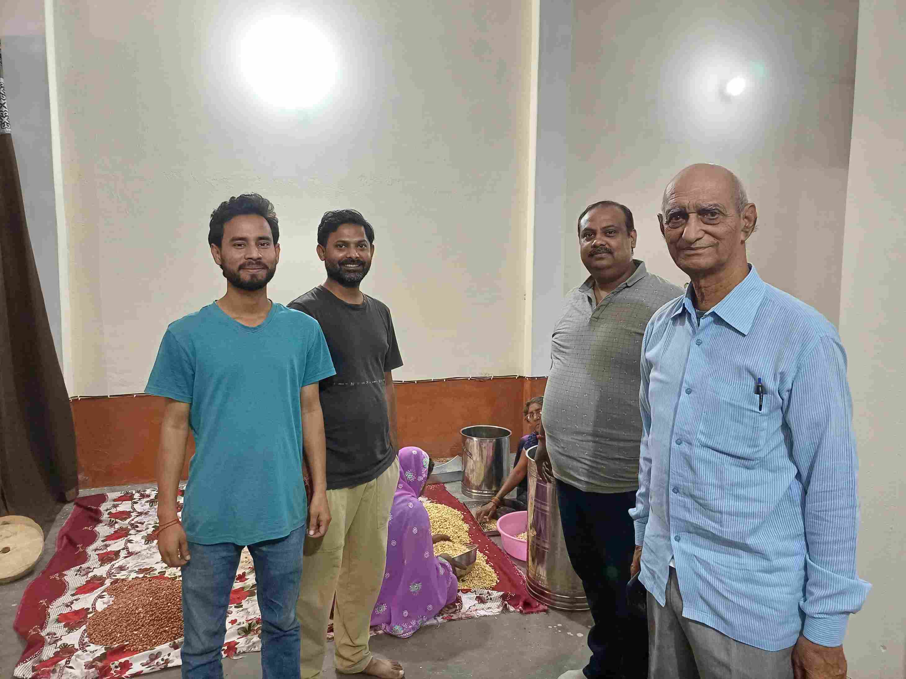 Aman Kumar and his co-founder pose with farmers at their primary processing space. 