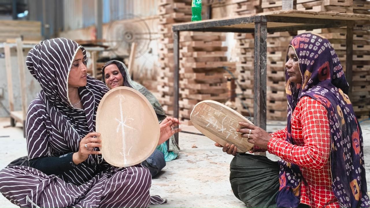 Traditional craftswomen, holding wooden kitchenware mid production