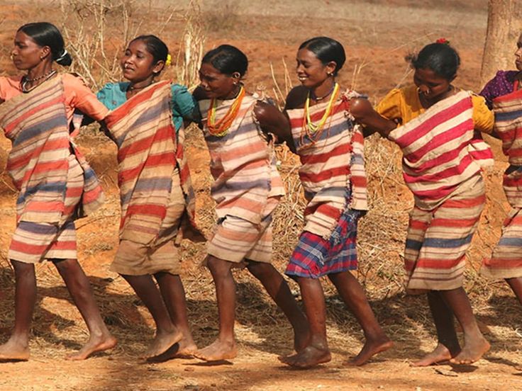 Tribal women dressed in traditional attire, dancing in a circle, performing rituals to honor their deities.