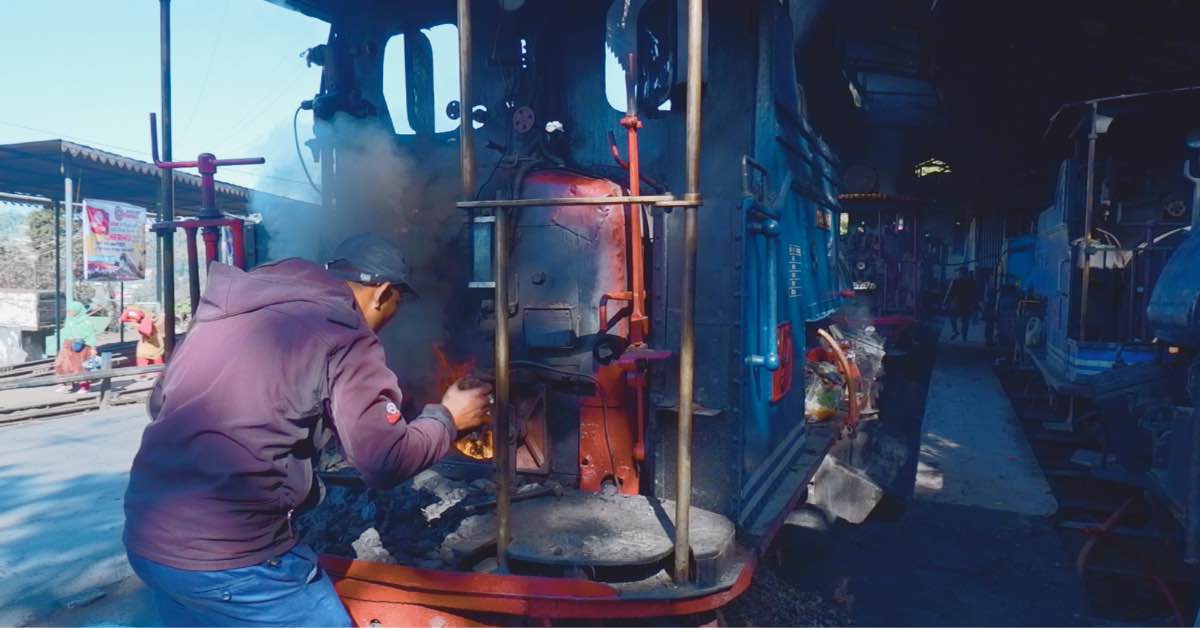 A DHR worker adds coal to the firebox of a stem engine near Darjeeling 