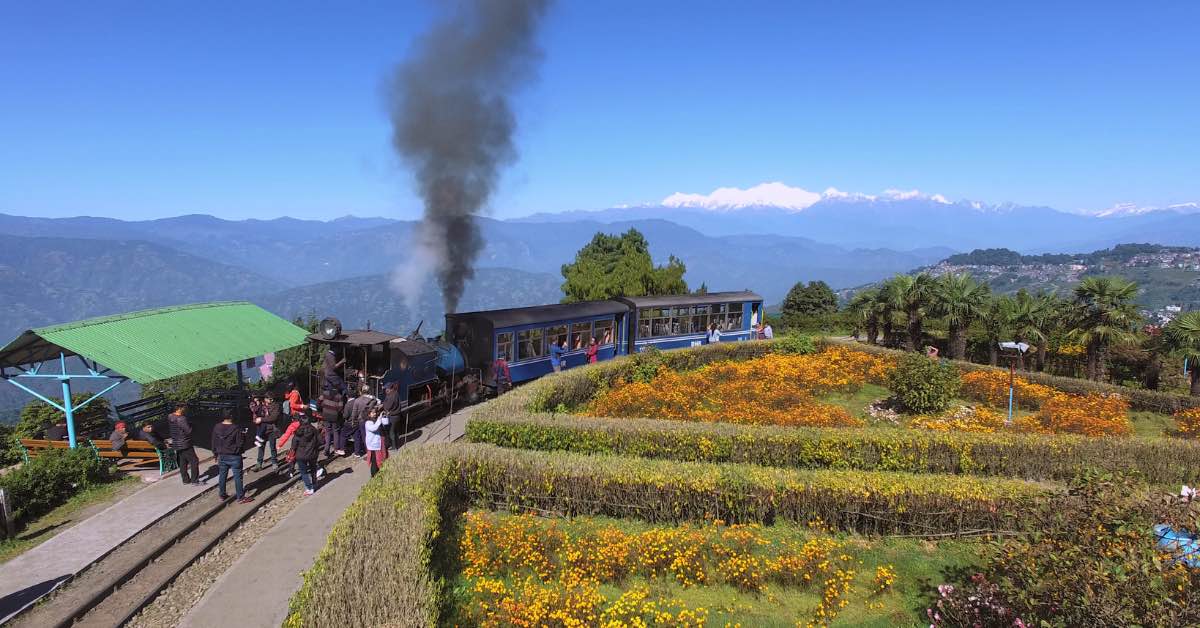 The Darjeeling Toy train chugs through Batasia Loop near Ghoom with the Kangchendzonga Range painting the background