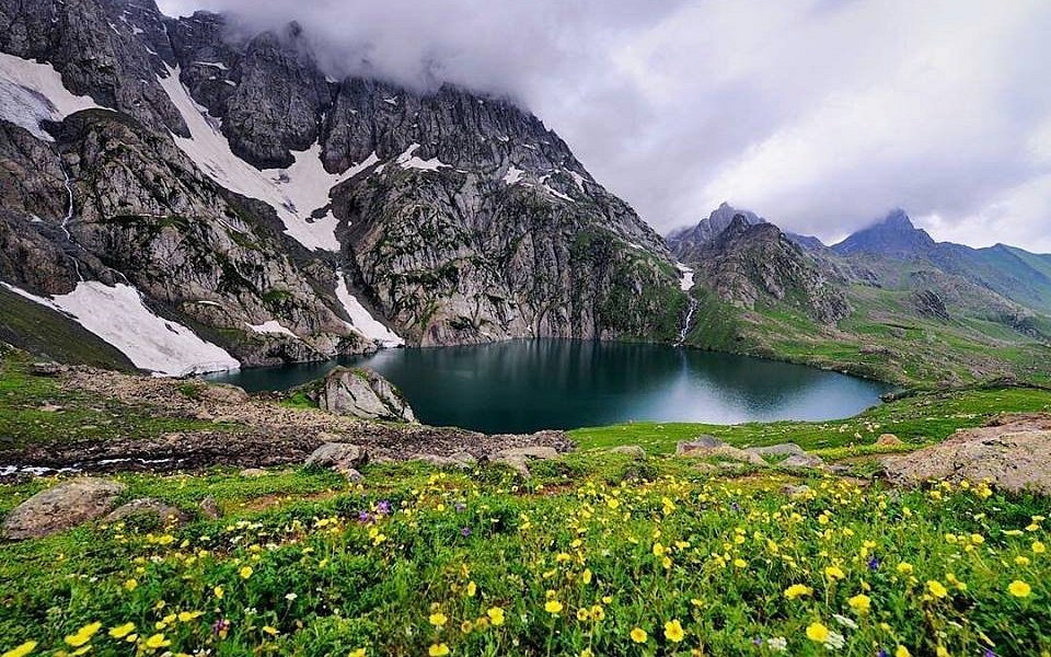 Gadsar Lake glows like a sapphire framed in snow — mysterious, magnificent, and wrapped in wildflowers.