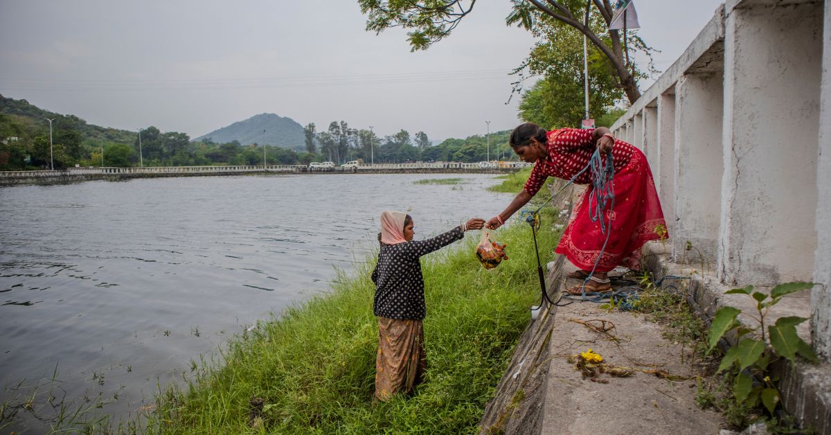 Tribal women Gyanwati and Bhanu clean Navratri offerings from the lake under the AMRUT initiative, reflecting community efforts to preserve this ancient water tower.