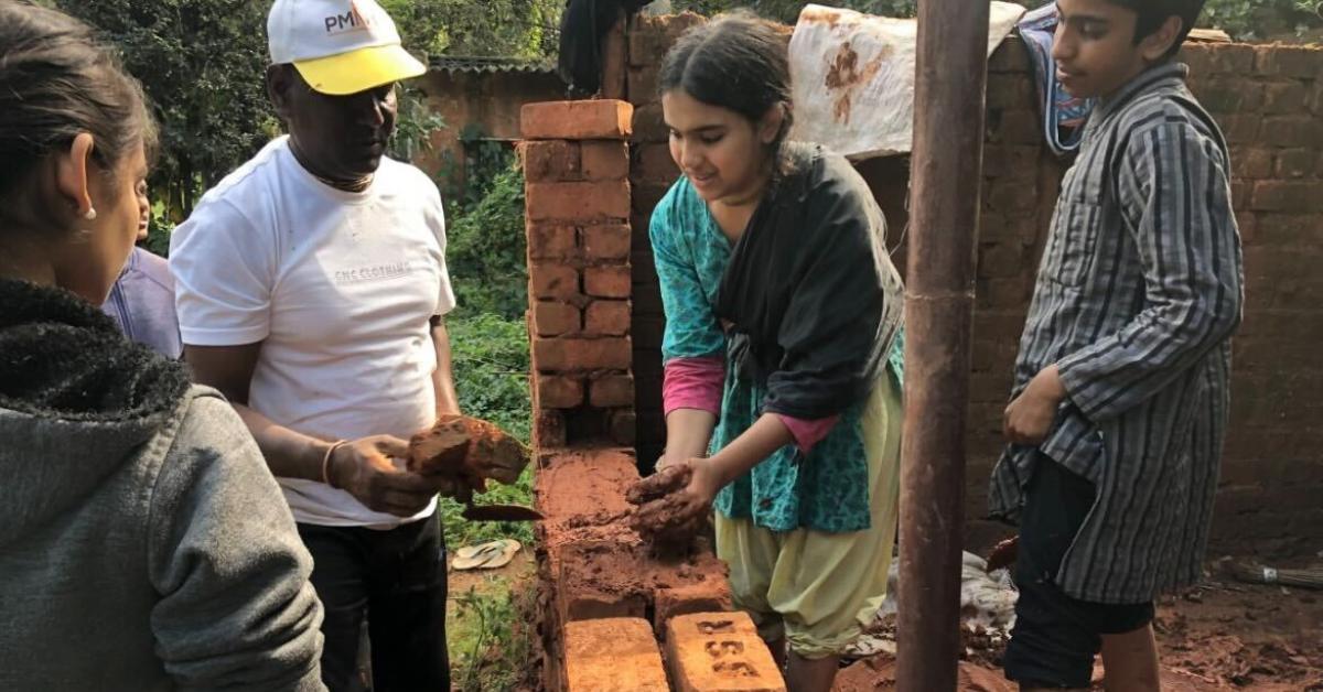 Hands-on learning includes construction skills, where children explore techniques of building with mud bricks.